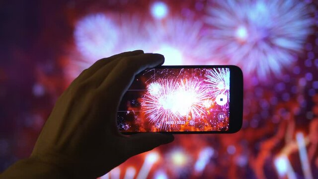 Person taking picture of the fireworks exploding show in 4K