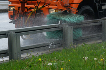 City cleaning service, rotating brush machine cleans the road separation fence. City cleanliness...