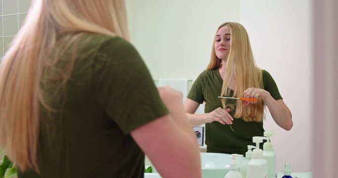 Woman cuts hair in the bathroom mirror for the first time