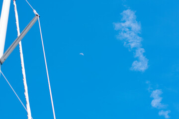 Moon, cloud, sailing boat mast in blue sky background