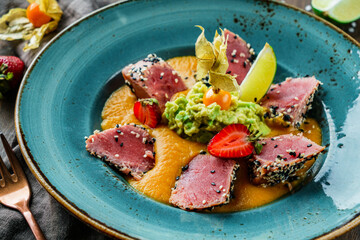 Fillet of tuna with lentil and avocado puree in plate on wooden background. Healthy food, seafood cuisine, top view