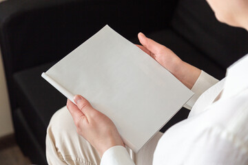 Hand holds white magazine with blank cover mock up. Hand in shirt hold clear magazine mockup template. A4 book softcover surface design.
