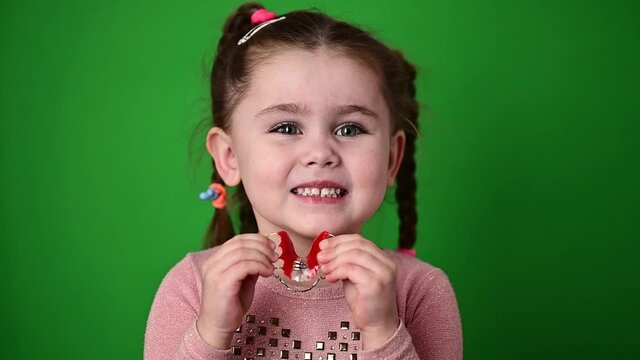 The child examines and demonstrates a dental plate to straighten crooked teeth.