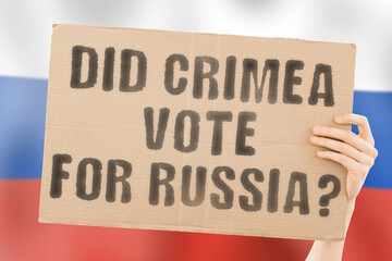 The question " Did Crimea vote for Russia? " on a banner in men's hand with blurred Russian flag on the background. Aggression. Occupation. International law. Territory