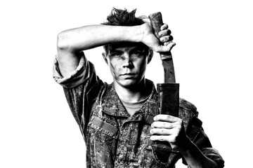 A young soldier in combat color pulls out a machete on a white background. Black and white contrast portrait.