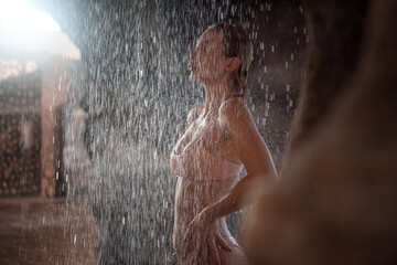 Fototapeta na wymiar Girl in a swimsuit under a waterfall
