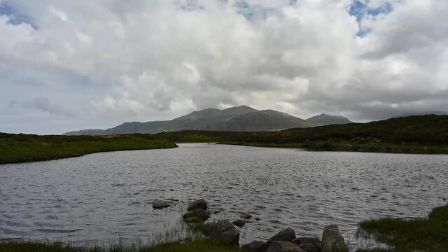 4k time lapse of dramatic cloud movement over South Uist mountains. Foreground of Loch Druidibeag nature reserve with rocks and water.