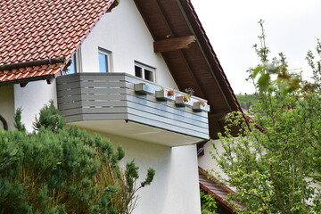Überdachter Dachbalkon und Balkon mit Metall-Geländer und lasiertenten Holzplanken als...