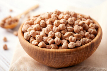 Raw chickpea beans in wooden bowl on kitchen table. Uncooked chickpeas