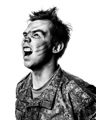 A young soldier in military uniform, a combat coloring with scars and bruises shouts against a white background. Black and white contrast portrait with white background.