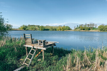 Beautiful lake with placing for fishing under blue sky on a sunny day. Scenic summer landscape, selective focus