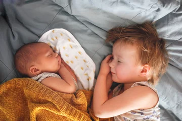 Fototapeten cute baby siblings sleep together, newborn baby and toddler older sister, sibling relationship in the family when the youngest was born © natalialeb