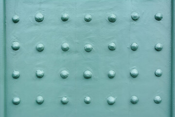 Rivets on a teal painted front door fragment