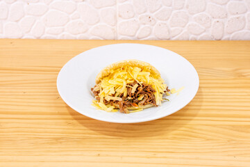 Arepa pelua with shredded meat and a lot of grated cheese