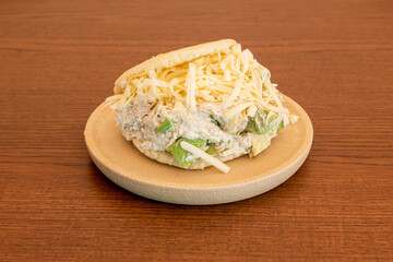Arepa sifrina with lots of avocado, mayonnaise and grated cheese in a round resin plate