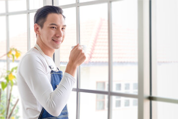 Portraitn Cutie man with coffee, handsome Asian man, Thai-Chinese bastard wearing white shirt. holding cup of tea drinking In morning time In relaxed, Modern businessman at coffee shop or cafe