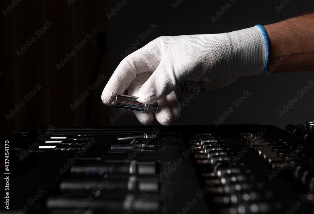 Wall mural male hand close up in white glove over open toolkit with metal tools for car and home repair, head.