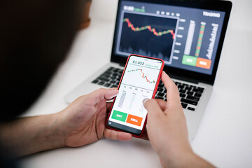 Fototapeta na wymiar Young business man trader investor using mobile phone app to analyze cryptocurrency financial stock market - Trading online and investment concept - Focus on hand holding the phone