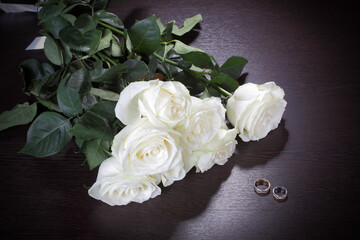 Bouquet of white roses and wedding rings on the table