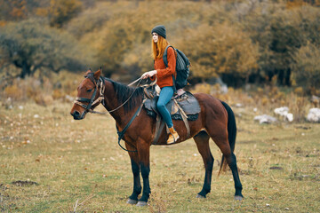 woman hiker rides a horse in a field mountains nature landscape