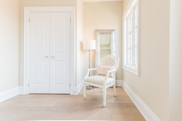 Chair in a Bright Room by a Window with Mirror behind and Closet Doors beside