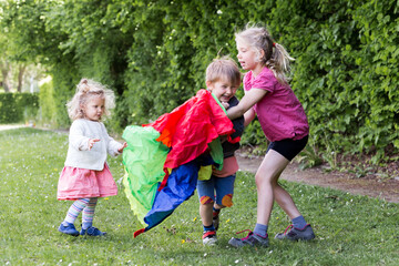 enfants jouent et se cachent sous une toile de parachute colorée