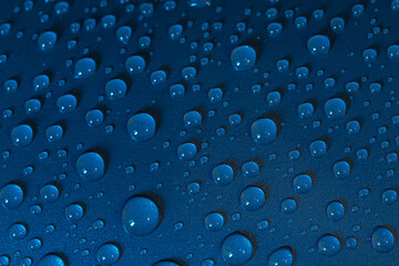 Selective focus of droplet raindrops on a shiny dark blue surface in raining day, Abstract cool water drop texture, Nature pattern background.
