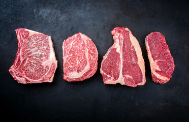 Raw dry aged wagyu porterhouse beef steak, entrecote and cutlet offered as top view on a rustic...