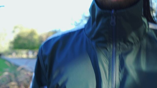 a man's hand zipping up his sports jacket in a park, getting ready to train. 4k video
