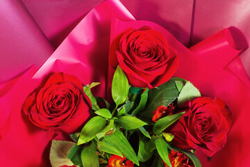 Red rose buds in a bouquet with red paper