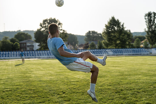 Full length soccer football player kicking the ball on game or training