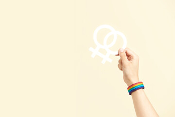Hand holding a symbol of the lesbian community, wearing an LGBT rainbow bracelet