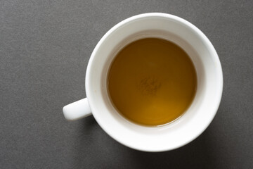 peppermint tea in a white mug or cup with a handle, photographed from above against a dark grey background