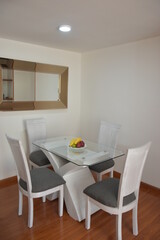 comedor con mesa de vidrio y sillas blancas de madera frutas y cuadros que decoran