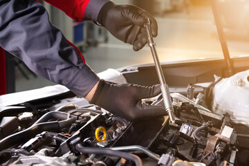 mechanic makes diagnostics of the car in the engine. car service and audit by an employee in a large car service. candle replacement. black mittens and car tool