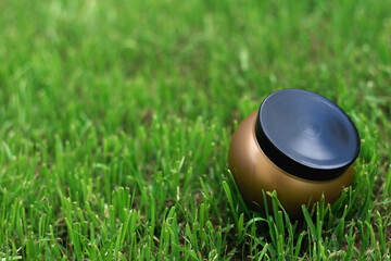 summer spa still life with a can of bronze cream on bright green grass. Flat lay top-down. Empty space for text.