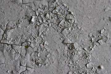 Peeling paint on the wall. Old concrete wall with cracked flaking paint. Weathered rough painted surface with patterns of cracks and peeling. Grunge texture for background and design. High resolution.