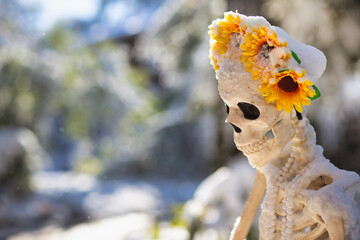 Skeleton head with a flower crown under the snow. Halloween decorations after snowstorm. Copy space for your text