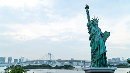 Fototapeta premium Statue of Liberty and rainbow bridge view at the afternoon time in Odaiba area, Tokyo, Japan