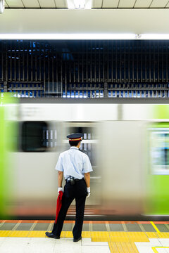 Abstract of Tokyo metro which the train is in moving motion and the platform staff is standing ready for giving signal to the train taken in Tokyo Japan which soft blurred focus applied.