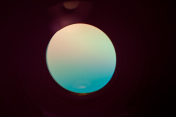 Abstract photo of the reflection of a cd through a small hole producing a space window like appearance