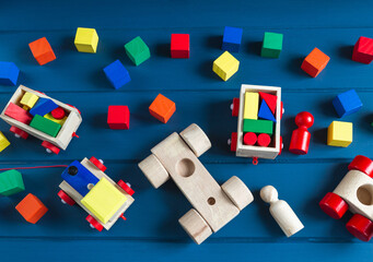 Multicolored wooden blocks, cars, train on blue background. Trendy eco-friendly puzzle toys.  Educational toys for kindergarten, preschool or daycare. Back to school