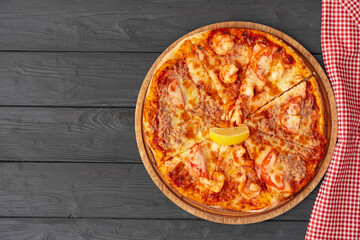 Top view of hot pizza on black wooden table