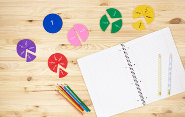 Colorful fractions in mathematics on the open notepad on wooden table. Interesting math for kids....