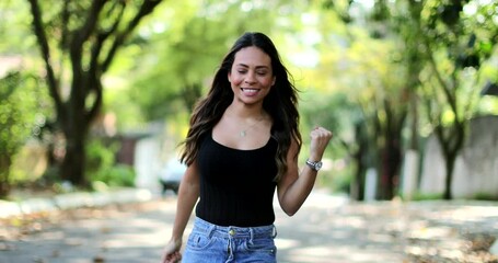 Excited Brazilian woman celebrating jumping with joy and happiness