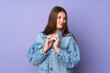 Teenager caucasian girl isolated on purple background scheming something