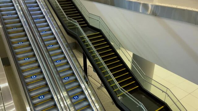 4K Empty Escalator moving upwards slowly at shopping mall near regular staircase. Architecture, infrastructure concept.
