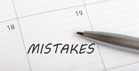 Text MISTAKES on calendar planner to remind you an important appointment with a pen on isolated white background.