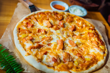 Homemade pizza on brown paper on wooden table with green leaf and white cream