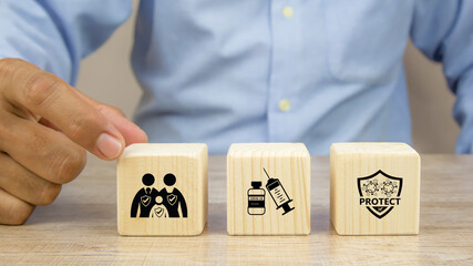 Close-up hand choose family with immunity protect with Covid-19 vaccine needle syringe on cube wooden toy block stack for prevent safety family medical and health and hospital for sick.